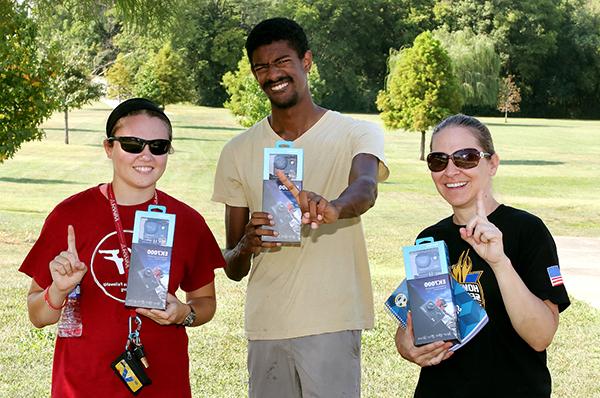 Three students holding their fingers up while smiling for a photo